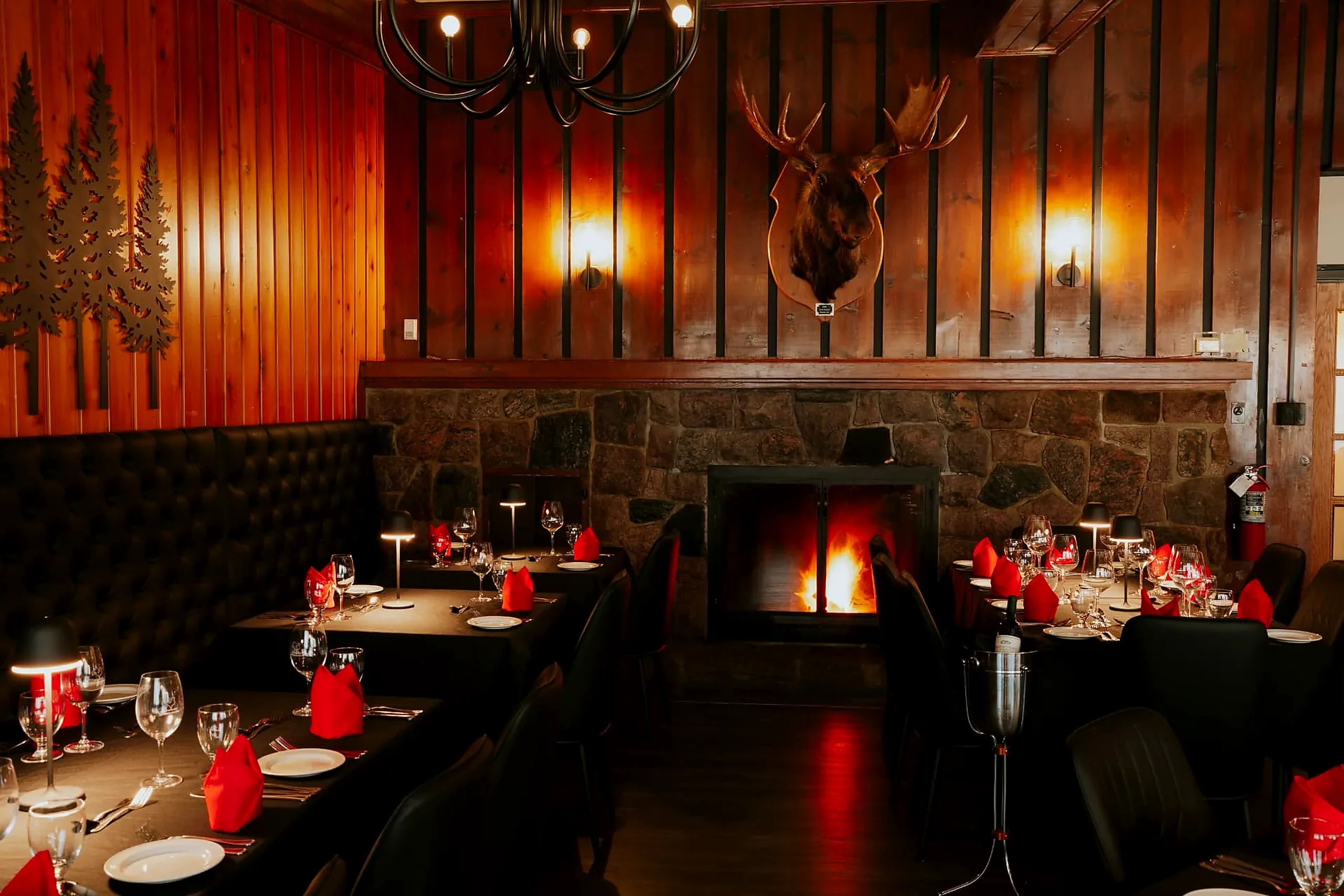 Dinner by the fire The Frozen Rooster dining room with the stone fireplace lit and tables set with red napkins